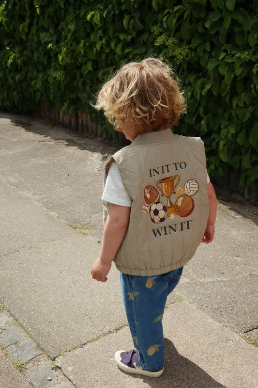 Juno Vest Konges Slojd mit In it to win it Schriftzug auf dem Rücken und detailreicher Fuß-, Base-, und Basketball Bestückung